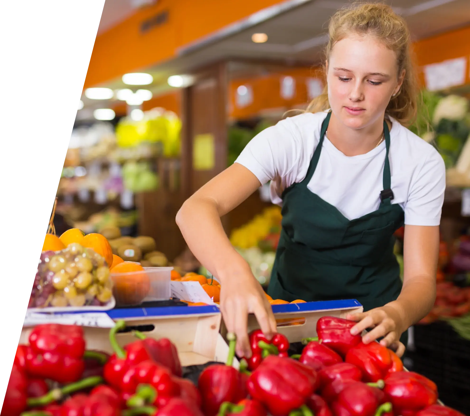 Grocery store employee stocking a shelf with red peppers