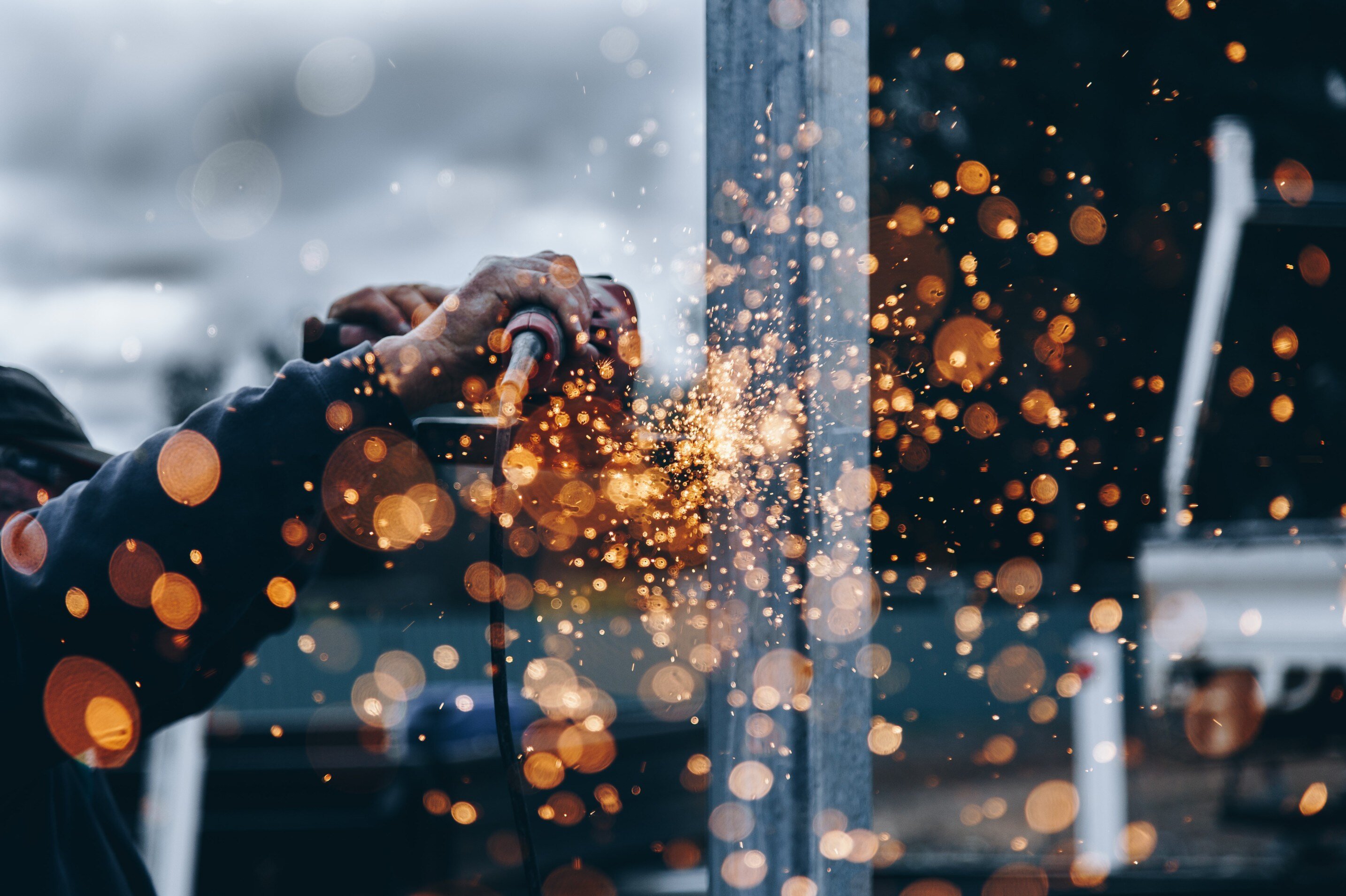 Worker using grinder to cut metal, sparks flying